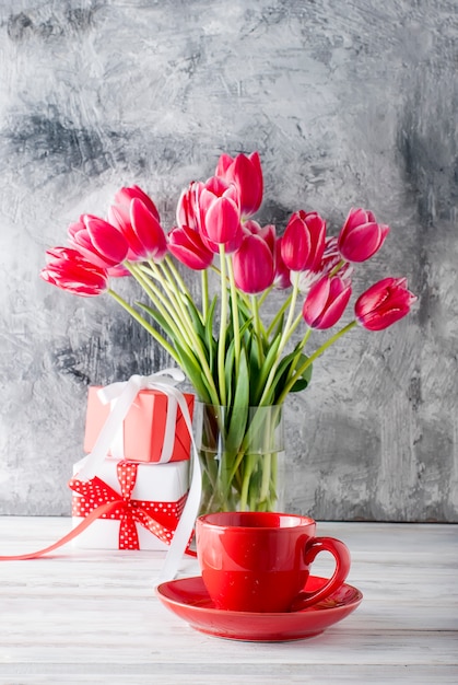 Bouquet di tulipani rosa, tazza di caffè e regalo.