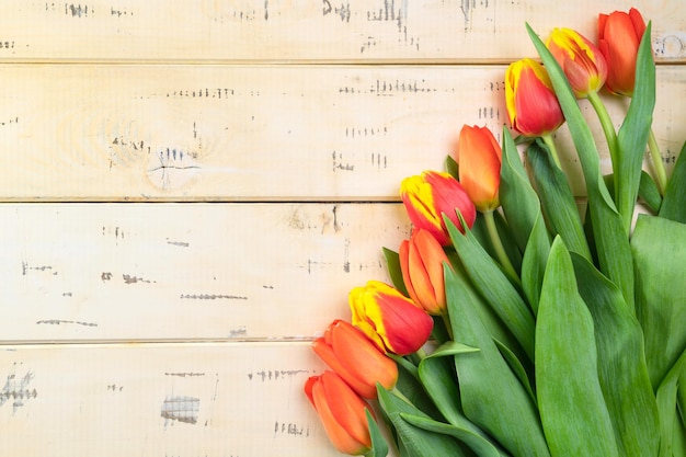 Bouquet di tulipani rossi su fondo di legno beige, copia-spazio