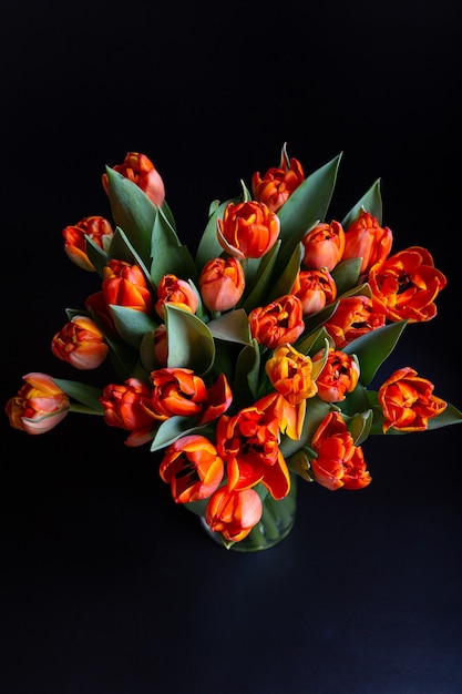 Bouquet di tulipani rosso-gialli su superficie nera