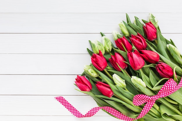 Bouquet di tulipani sulla parete in legno bianco.