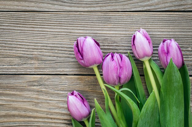 Bouquet di tulipani viola su una superficie in legno vista dal alto