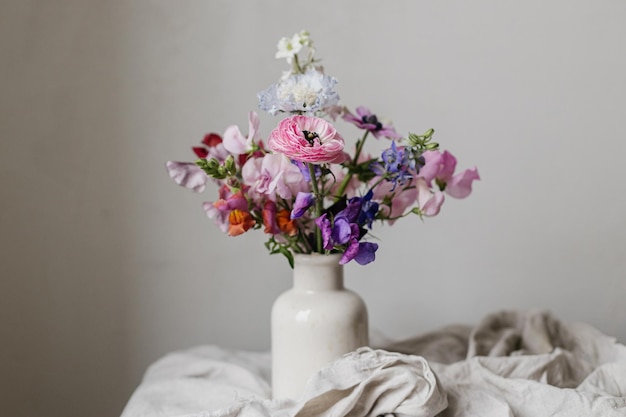Bouquet elegante su uno sfondo di lino rustico Bella anemone colorata Ranunculus lathyrus scabiosa in vaso Fiori estivi Fiori floreali natura morta di umore Spazio per il testo