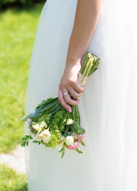 bouquet leggero della sposa in mano sullo sfondo di un abito bianco