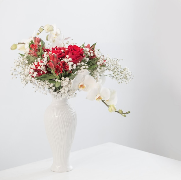 Bouquet rosso e bianco in vaso su sfondo bianco