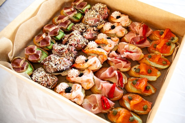 Box con panini, bruschette con affettati, formaggi e frutti di mare. Snack gourmet per catering a buffet per feste