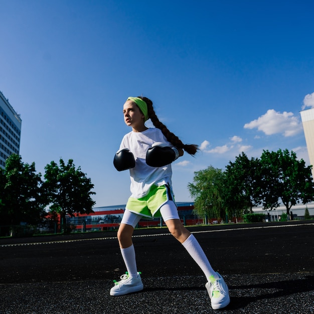 Boxer bambino femminile in guanti, concetto di femminismo. Ritorno a scuola, lezione di preparazione fisica.