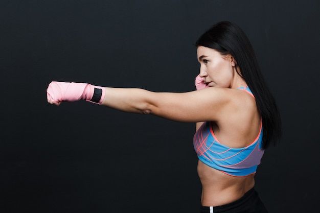 Boxer donna forte muay thai sportiva in posa in studio di formazione a sfondo nero