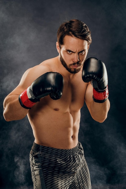 Boxer senza camicia con guanti su sfondo scuro in fumo