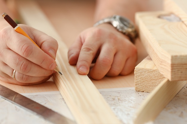 Braccia dell'operaio che misurano barra di legno