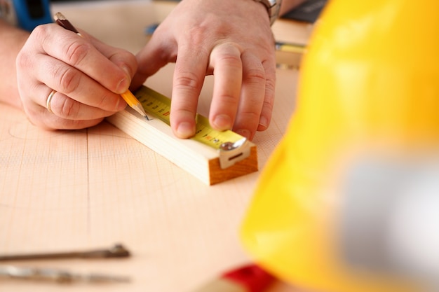 Braccia dell'operaio che misurano il primo piano di legno della barra