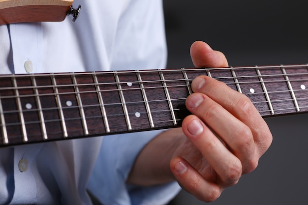 Braccia maschili suonando la chitarra classica di forma