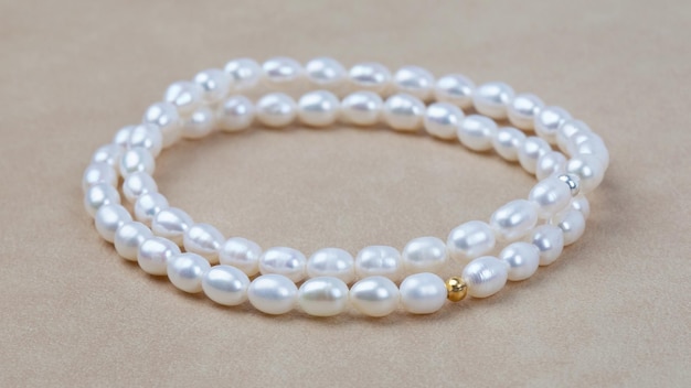 Braccialetti di perle barocche eleganti di lusso su fondo in pelle martellata beige. Messa a fuoco selettiva. Primo piano