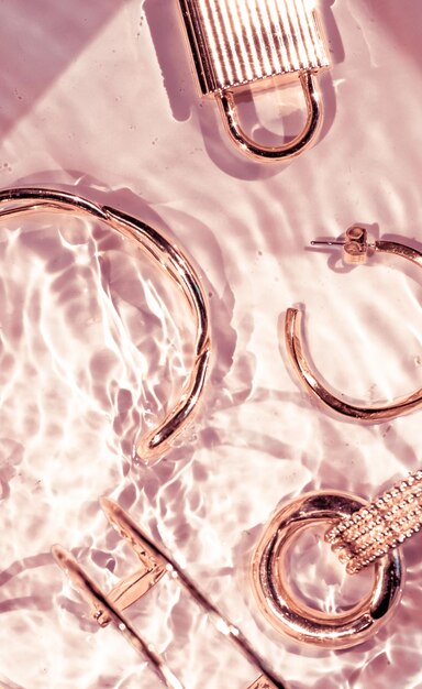 Braccialetti in oro rosa orecchini anelli gioielli su sfondo rosa acqua glamour di lusso e design di bellezza per le vacanze per annunci di marchi di gioielli