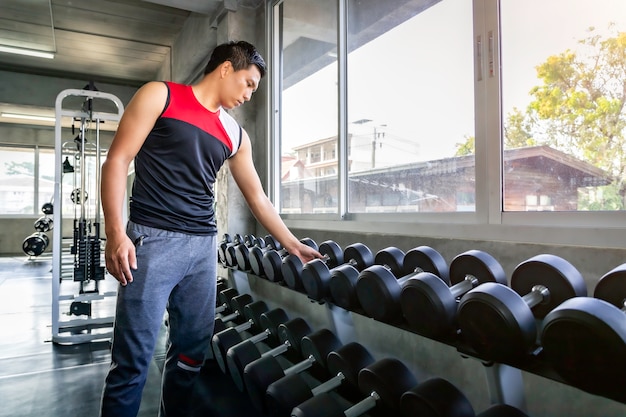 Braccio asiatico atletico di allenamento dell'uomo forte culturista perfetto con la testa di legno sulla palestra.