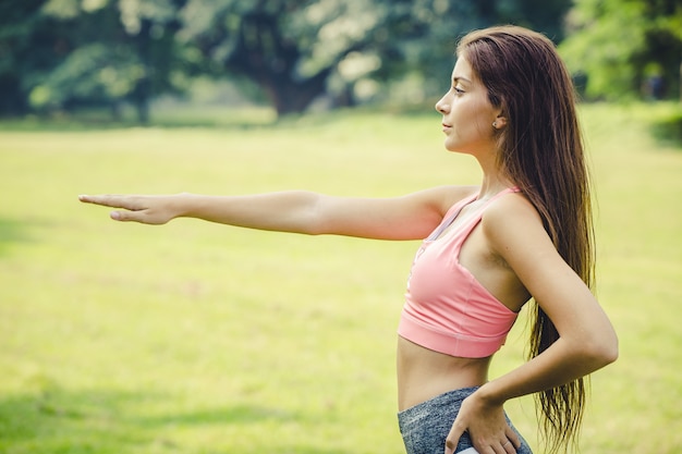 braccio della ragazza sportiva che si estende per riscaldare i muscoli del corpo prima e dopo l'esercizio vista laterale all'aperto