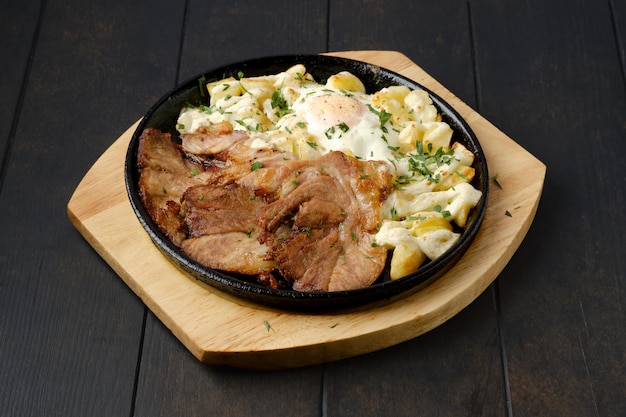 Braciola di maiale fritta con patate e uova su un piatto