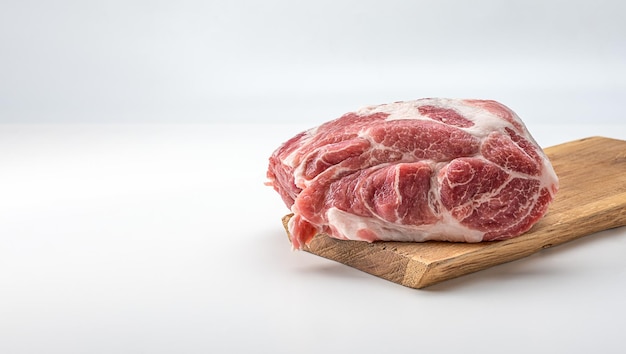 Braciola di spalla di maiale cruda su tavola di legno isolata su bianco. Bistecca di maiale cruda. Pezzo di carne rossa fresca sulla macelleria, mercato.