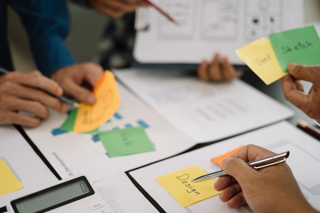 Brainstorming del designer dell'interfaccia utente sul design wireframe dell'interfaccia dell'app mobile con breif del cliente e codice colore in ufficio