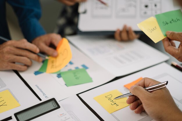 Brainstorming del designer dell'interfaccia utente sul design wireframe dell'interfaccia dell'app mobile con breif del cliente e codice colore in ufficio