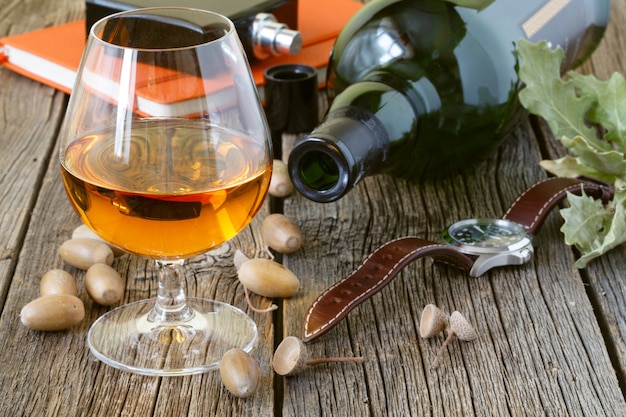 Brandy e foglie secche di quercia su un tavolo di legno