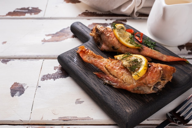 Branzino al forno con il limone del pepe del pomodoro e le erbe sul bordo di legno