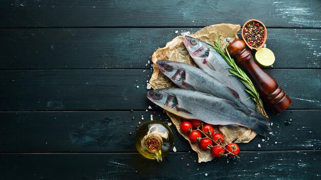 Branzino di pesce di mare Frutti di mare su sfondo di pietra nera Vista dall'alto Spazio di copia gratuito