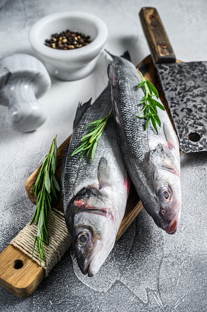 Branzino di pesce fresco crudo e ingredienti per cucinare. Sfondo bianco. Vista dall'alto.