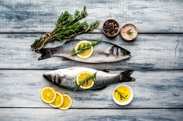 Branzino di pesce fresco. Pesce crudo del branzino con le spezie e le erbe degli ingredienti su fondo di legno