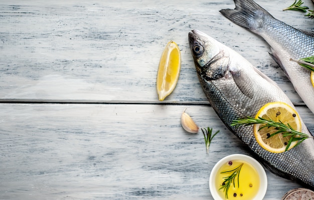 Branzino di pesce fresco. Pesce crudo del branzino con le spezie e le erbe degli ingredienti su fondo di legno