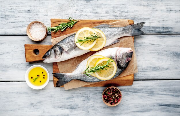 branzino e pesce dorado con limone e spezie su fondo di legno