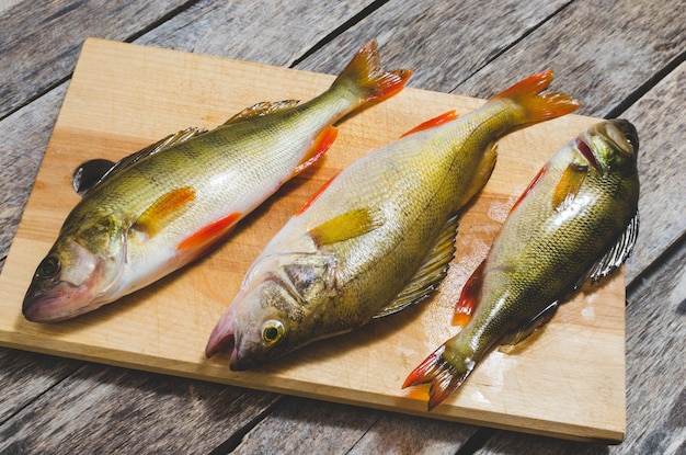 Branzino sul taglierePesce predatore su uno sfondo di legno primo piano