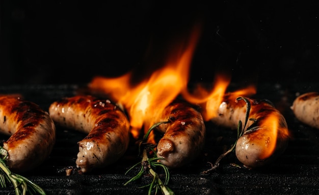 Bratwurst di salsiccia alla griglia che cucinano sulla griglia ardente Griglia per barbecue sfrigolante su carboni ardenti ardenti carne alla griglia in acciaio Formato banner lungo