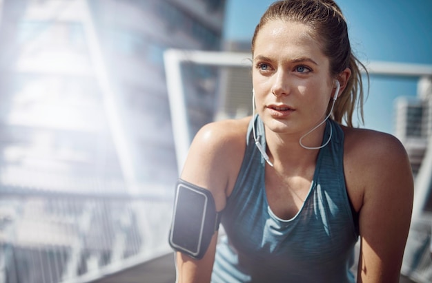 Break donna che pensa e corridore in città con le cuffie per l'esercizio di jogging mattutino e l'allenamento all'aperto atleta che si allena stanco e ragazza sul ponte per correre sfida fitness e playlist musicale
