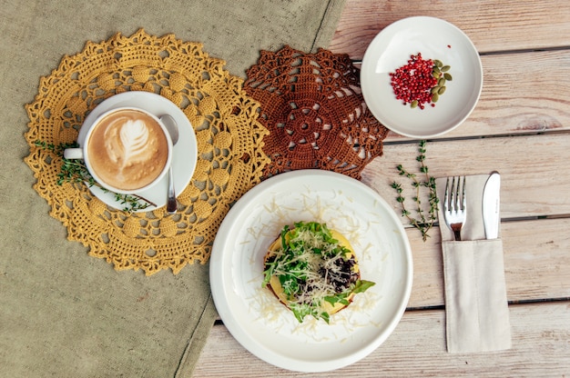 Breakfest con caffè e sandwich sul tavolo di legno con forchetta e coltello