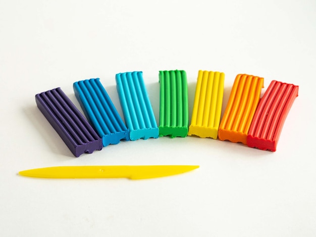 Bricchetti di plastilina di colori arcobaleno e una pila gialla per tagliare la massa di plastica Crea per bambini