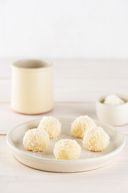 Brigadeiro di tartufi caramellati con cocco su un piatto su un tavolo di legno chiaro