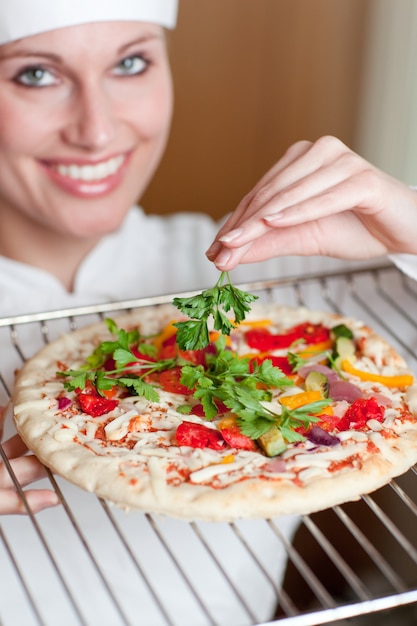 Brillante cuoco femminile che cucina una pizza