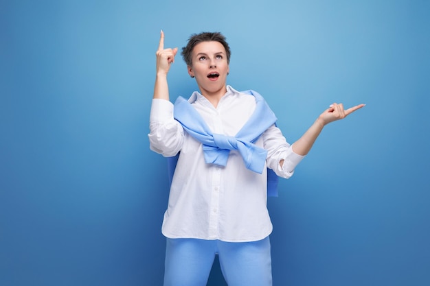 Brillante giovane donna con un taglio di capelli corto in una camicia bianca e pantaloni blu con un'idea in testa