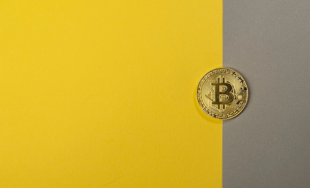 Brillante moneta bitcoin su sfondo giallo e grigio alla moda con spazio di copia