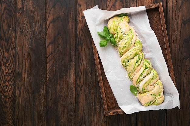 Brioche al pesto di aglio selvatico intrecciato Pane fresco fatto in casa con pesto di aglio selvatico su tavola di legno su tavola di fondo in legno Pane italiano Spazio di copia Vista dall'alto