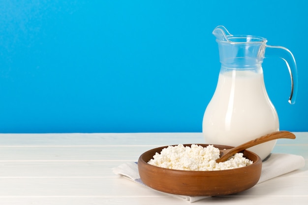 Brocca di vetro di latte e ciotola di ricotta sulla tavola di legno