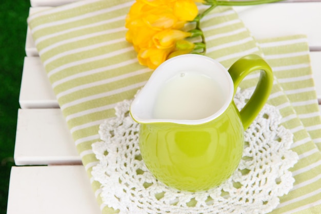 Brocca verde con latte sul tovagliolo sul tavolo da picnic in legno primo piano