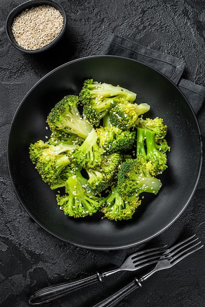 Broccoli bolliti con spezie in un piatto. Sfondo nero. Vista dall'alto.