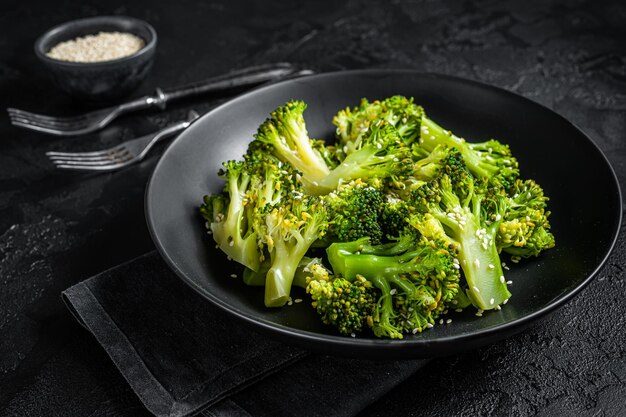 Broccoli bolliti con spezie in un piatto. Sfondo nero. Vista dall'alto.