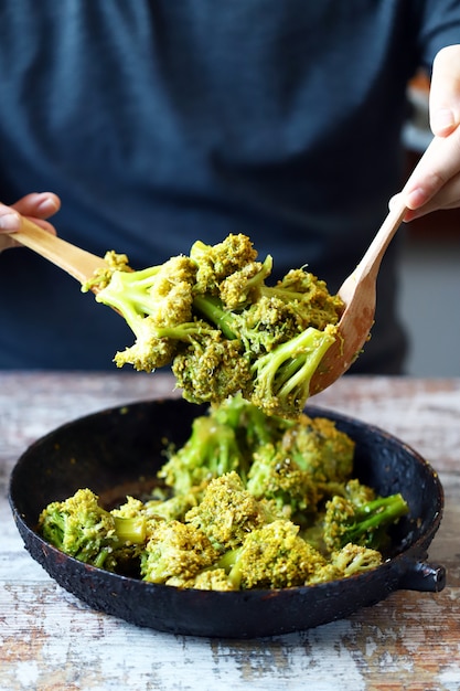 Broccoli cotti in padella. Lo chef mescola broccoli. Cibo sano.