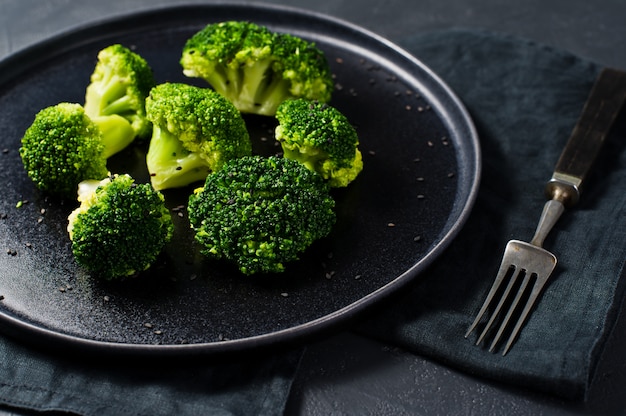 Broccoli crudi su un piatto nero.