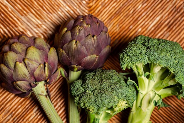 Broccoli e carciofi su sfondo di legno Cibo sano e vegano Broccoli di cavolo verde e carciofi viola