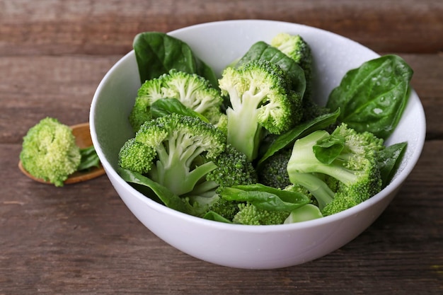 Broccoli freschi con spinaci in una ciotola sul tavolo di legno si chiuda