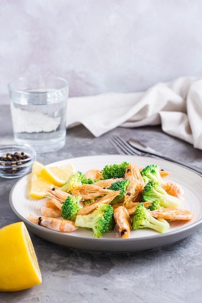 Broccoli fritti e gamberetti su un piatto sul tavolo Cibo vegetariano sano Vista verticale Spazio di copia