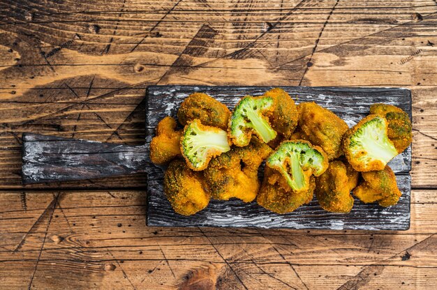 Broccoli impanati al forno su una tavola di legno con le erbe